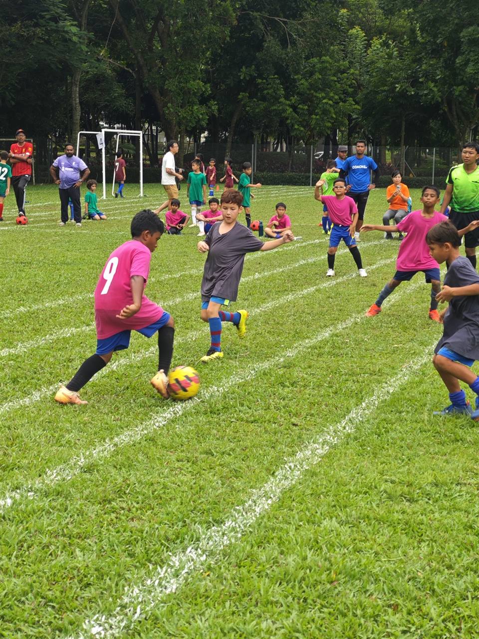 Player in pink bib dribbling past a defender during a tournament match
