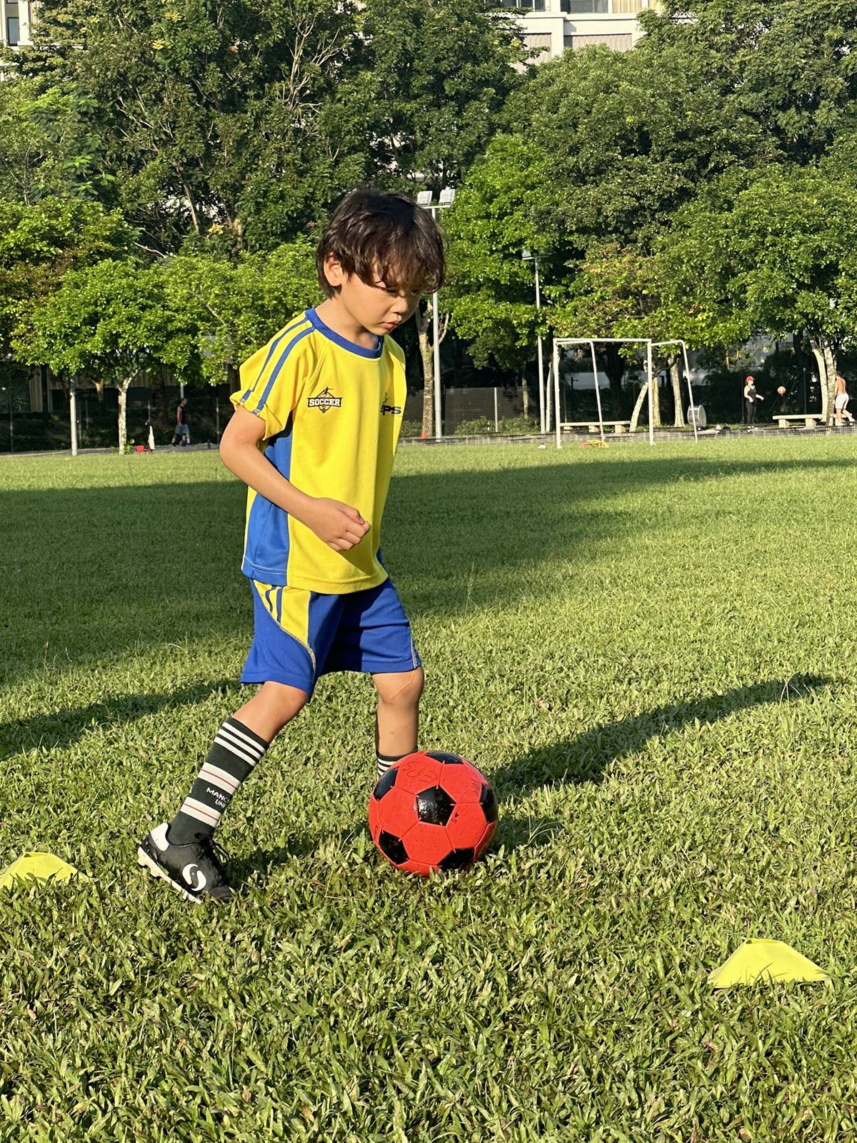 Young EPS footballer dribbling the ball through cones at Desa Park City