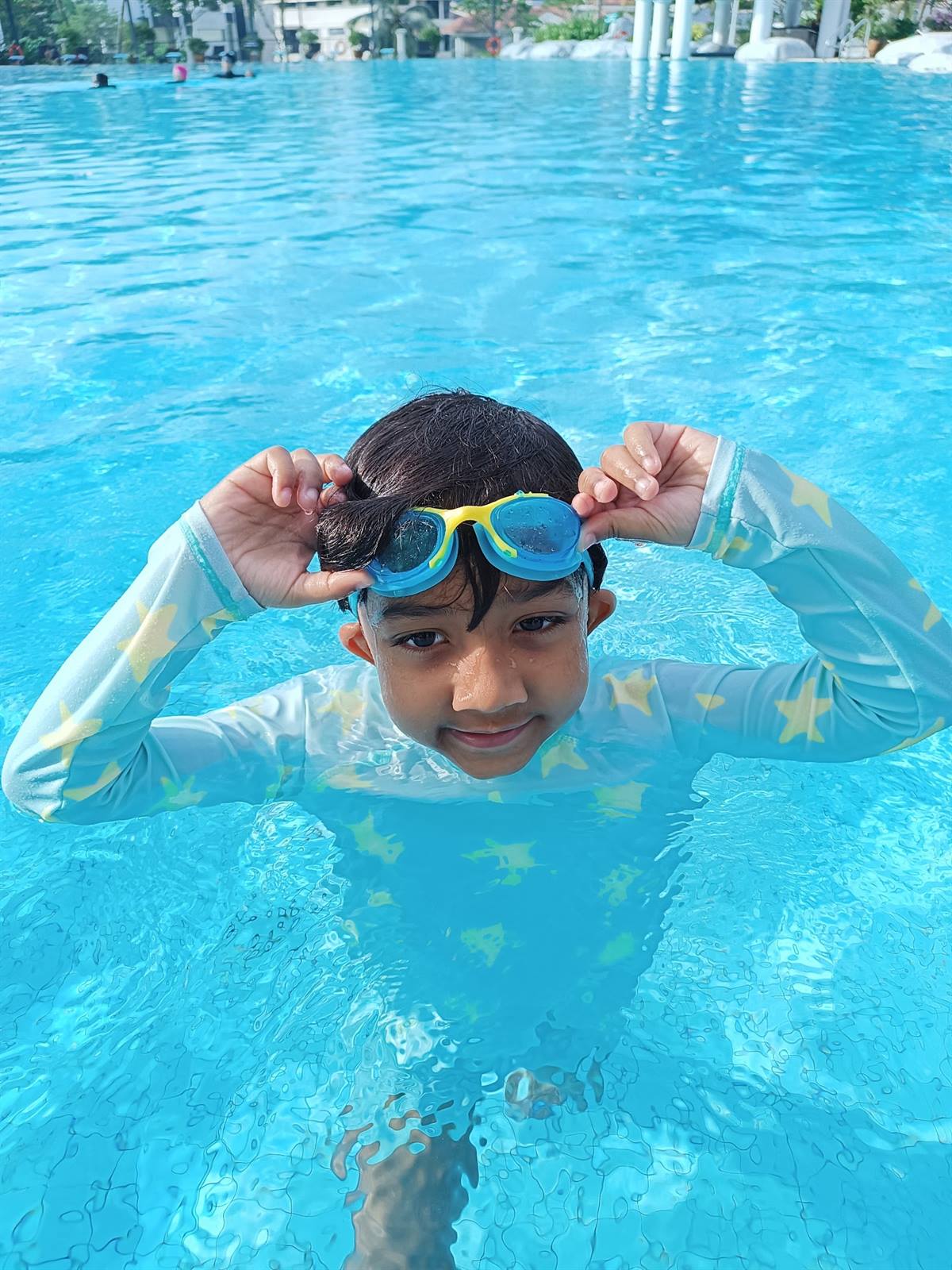 Smiling young swimmer adjusting goggles in the pool