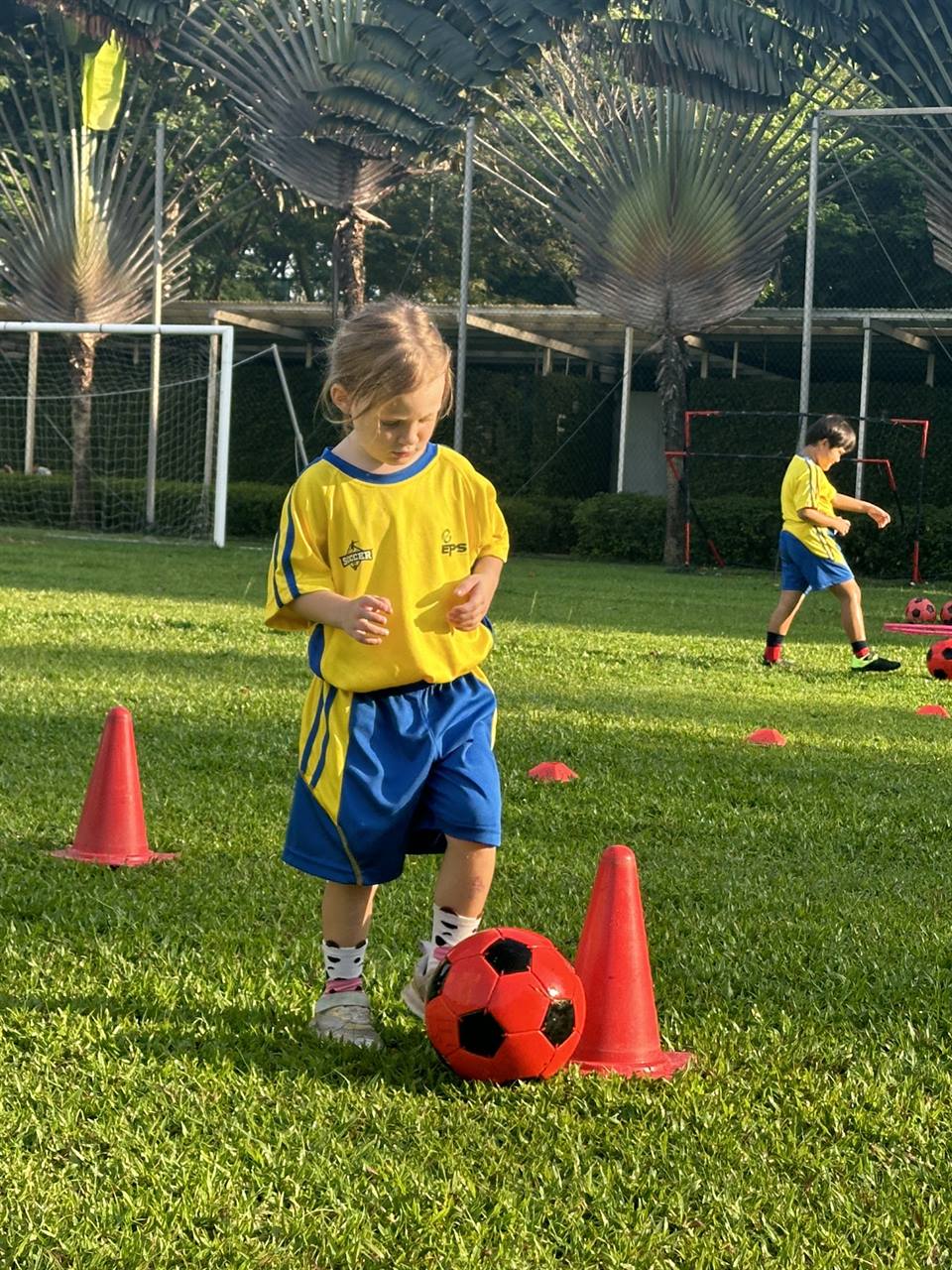 Young player dribbling between cones